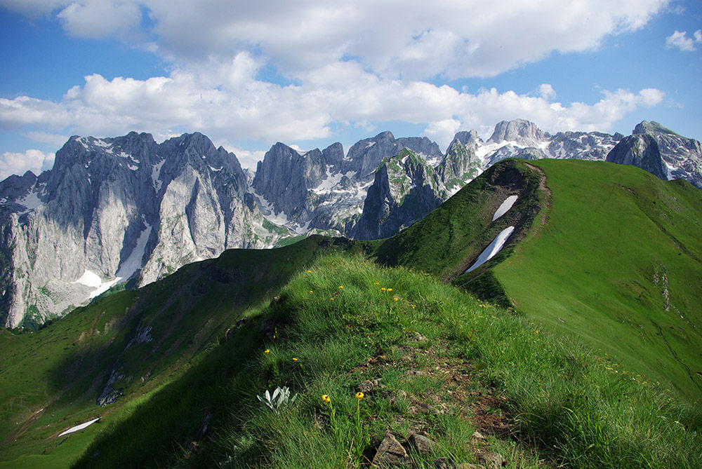 Prokletije – Dolina Grebaje je jedna od najimpresivnijih i najautentičnijih planinskih destinacija na sjeveru Crne Gore. Pješačke i planinarske staze vode kroz netaknute šume, planinske potoke i strme litice, pružajući panoramski pogled na vrhove Karanfile i okolne masive. Svaki korak otkriva kristalno čiste izvore, bogat biljni i životinjski svijet, a mir planinskih dolina omogućava potpuni bijeg od svakodnevnice.
Ruta obuhvata raznolike staze – od laganih šetnji do zahtjevnih planinarskih uspona, pogodne i za početnike i za iskusne avanturiste. Duž puta nalaze se autentični katuni, gdje posjetioci mogu upoznati život planinskih pastira, kušati domaće proizvode poput sira i meda, te osjetiti autentičnu planinsku atmosferu. Katuni su i idealne tačke za odmor, fotografisanje i upijanje impresivnih pogleda na okolicu.
Za ljubitelje aktivnog odmora, Prokletije – Dolina Grebaje nude brojne mogućnosti: trekking, planinarenje, fotografisanje, promatranje ptica i divljih životinja, pa čak i kampovanje u netaknutoj prirodi. Strme litice i planinski vrhovi pružaju adrenalinske izazove, dok mirne doline i izvori omogućavaju opuštanje i povezivanje s prirodom.
Ova destinacija spaja spektakularne pejzaže, avanturu i kulturno nasljeđe, čineći Prokletije – Dolina Grebaje idealnim izborom za sve koji žele da dožive autentičnu Crnu Goru u njenom planinskom i netaknutom obliku. Svaki posjetilac može ovdje pronaći svoju kombinaciju avanture, odmora i prirodne ljepote.
